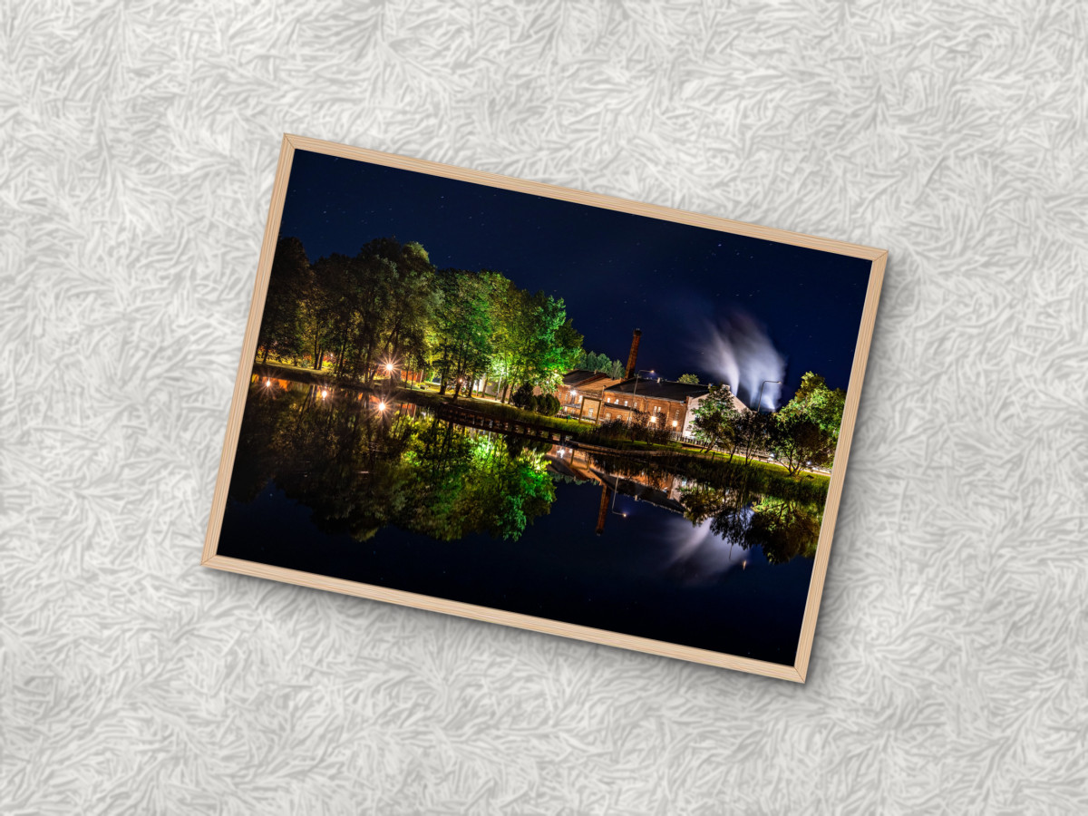 Puitraamis fotoplakat öise vabrikufotoga valgel karvasel vaibal
