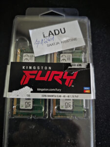 Clamshell packaging for Kingston Fury DDR5 memory sticks with a white label showing 'LADU' and handwritten blue numbers; black Fury branding visible beneath.
